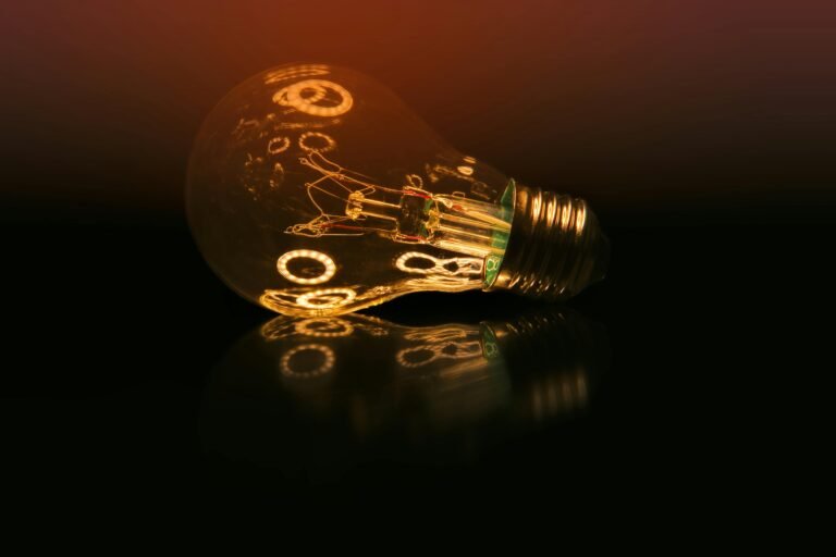 A glowing light bulb on a dark reflective surface creating a warm ambient atmosphere.